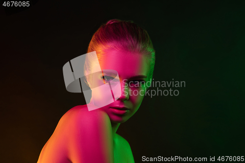 Image of Portrait of female fashion model in neon light on dark studio background.