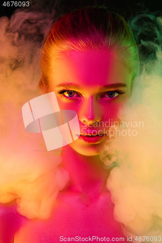 Image of Portrait of female fashion model in neon light on dark studio background.