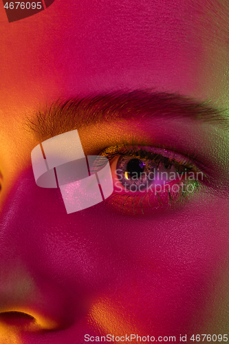 Image of Close up portrait of female fashion model in neon light on dark studio background.