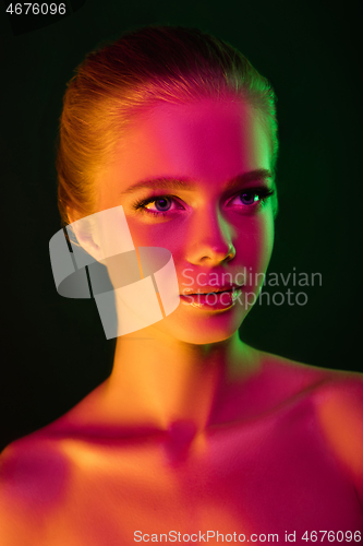 Image of Portrait of female fashion model in neon light on dark studio background.