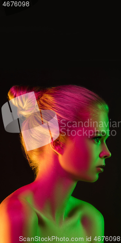 Image of Portrait of female fashion model in neon light on dark studio background.