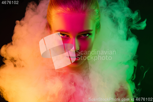 Image of Portrait of female fashion model in neon light on dark studio background.