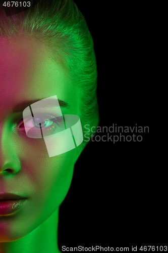 Image of Portrait of female fashion model in neon light on dark studio background.