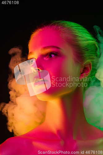 Image of Portrait of female fashion model in neon light on dark studio background.