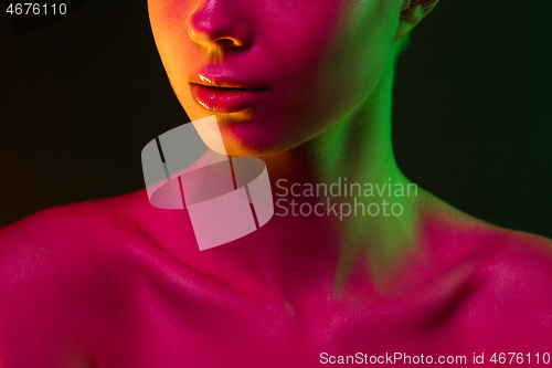 Image of Close up portrait of female fashion model in neon light on dark studio background.