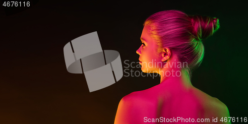 Image of Portrait of female fashion model in neon light on dark studio background.