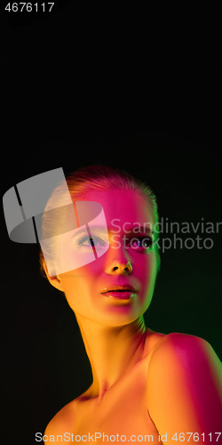 Image of Portrait of female fashion model in neon light on dark studio background.