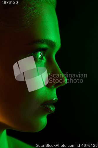 Image of Portrait of female fashion model in neon light on dark studio background.