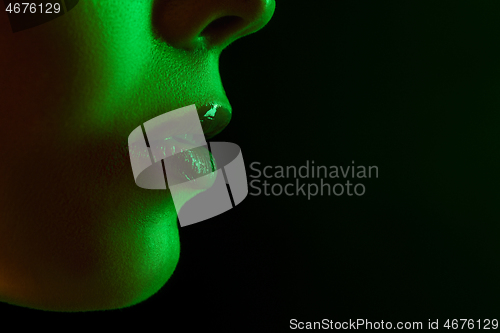 Image of Close up portrait of female fashion model in neon light on dark studio background.