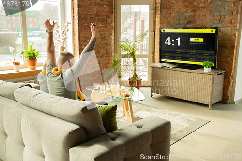 Image of TV screen with mobile app for betting and score, cheering friends, fans in front of it look excited