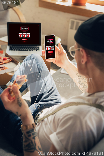 Image of Man holding smartphone its screen with mobile app for online casino lottery