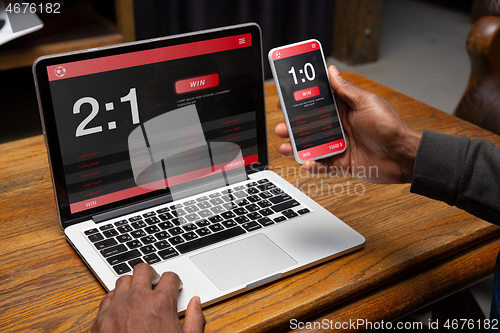 Image of Close up laptop and smartphone screen with mobile app for betting and score