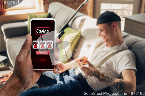 Image of Device screen with mobile app for online casino lottery, cheering man, winner on background