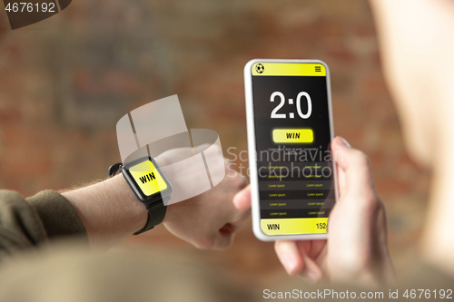 Image of Close up watch and smartphone screen with mobile app for betting and score