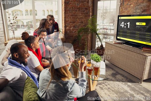 Image of TV screen with mobile app for betting and score, cheering friends, fans in front of it look excited