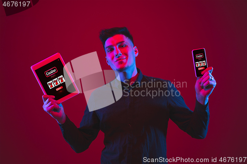 Image of Man holding smartphone, tablet its screen with mobile app for online casino lottery