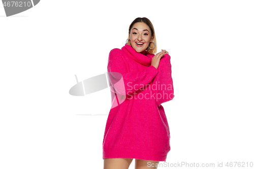 Image of Beautiful young woman in bright pink comfortable sweater, long sleeve isolated on white studio background