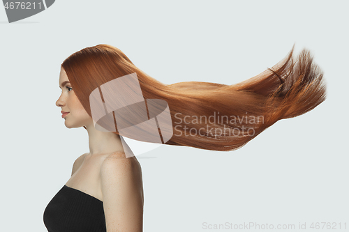 Image of Beautiful model with long smooth, flying red hair isolated on white studio background.