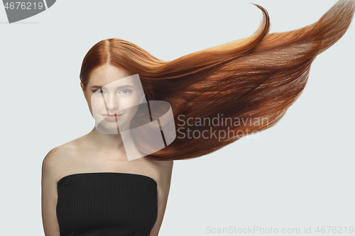 Image of Beautiful model with long smooth, flying red hair isolated on white studio background.