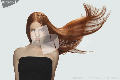 Image of Beautiful model with long smooth, flying red hair isolated on white studio background.