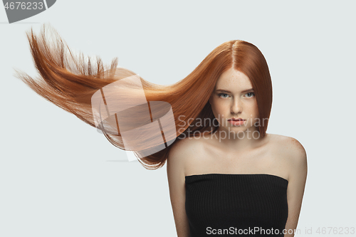 Image of Beautiful model with long smooth, flying red hair isolated on white studio background.