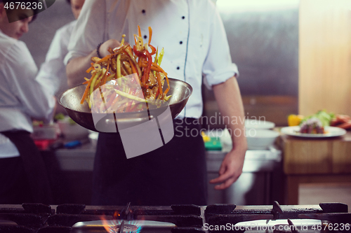 Image of chef flipping vegetables in wok