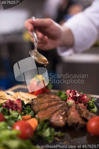 Image of Chef hand finishing steak meat plate