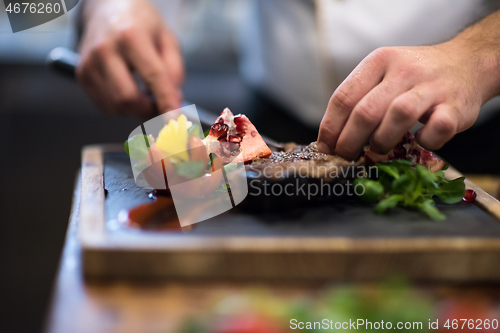 Image of closeup of Chef hands serving beef steak