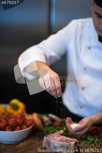 Image of Chef putting salt on juicy slice of raw steak