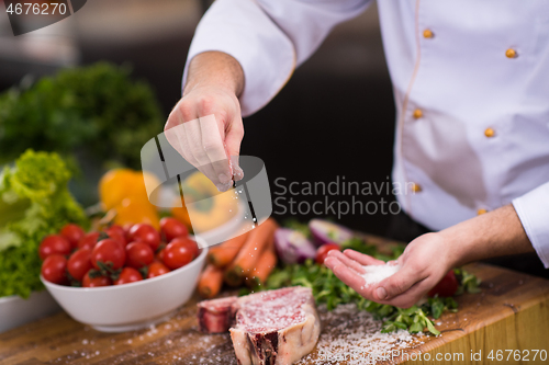 Image of Chef putting salt on juicy slice of raw steak