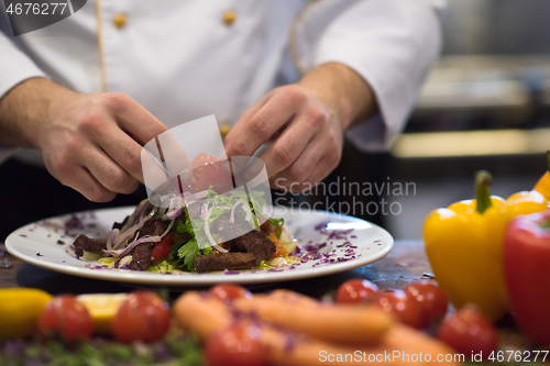 Image of cook chef decorating garnishing prepared meal