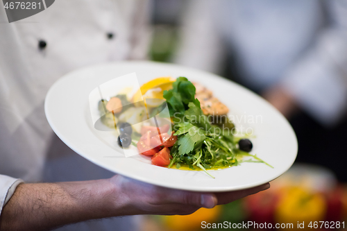 Image of Chef hands holding dish of fried Salmon fish fillet