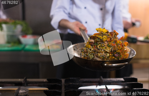 Image of chef flipping vegetables in wok