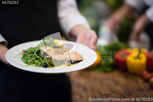 Image of Chef hands holding dish of fried Salmon fish fillet