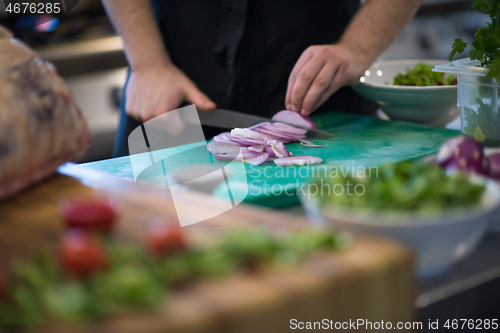 Image of Chef  hands cutting the onion with knife