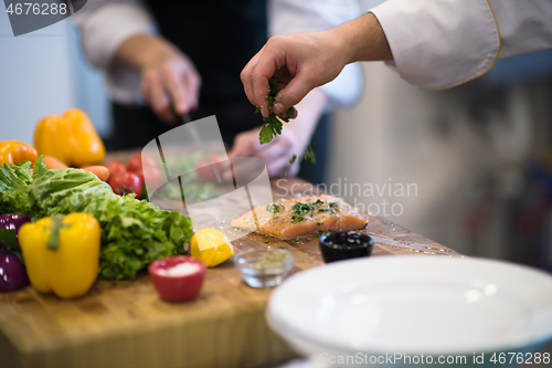 Image of Chef hands preparing marinated Salmon fish