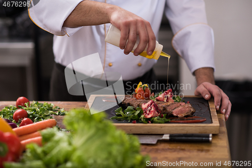 Image of Chef finishing steak meat plate