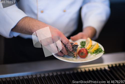 Image of chef hands cooking grilled salmon fish