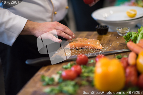 Image of Chef hands preparing marinated Salmon fish