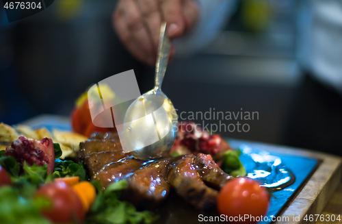 Image of Chef hand finishing steak meat plate