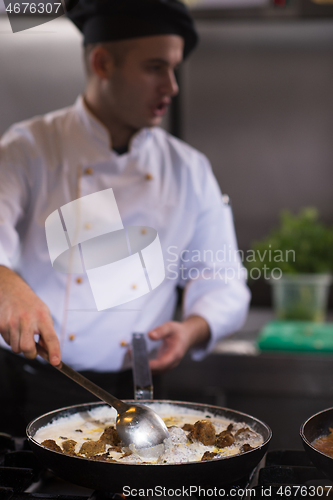 Image of chef preparing food, frying in wok pan