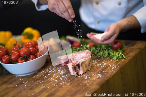 Image of Chef putting salt on juicy slice of raw steak