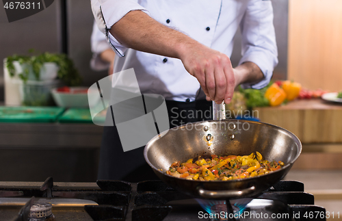 Image of chef putting spices on vegetables in wok