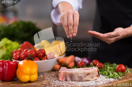 Image of Chef putting salt on juicy slice of raw steak