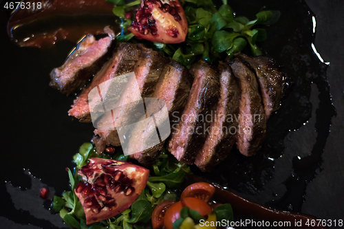 Image of Juicy slices of grilled steak on wooden board