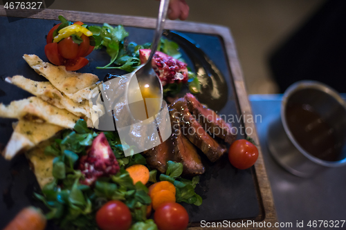 Image of Chef hand finishing steak meat plate