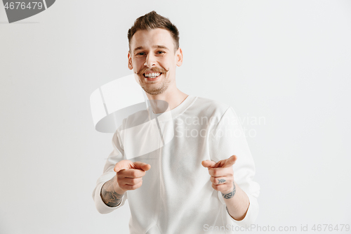 Image of The happy businessman standing and smiling against gray background.