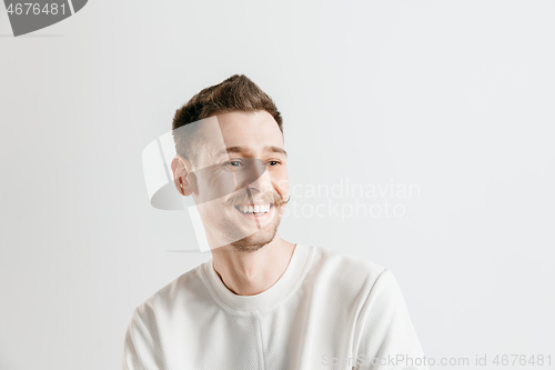 Image of The happy businessman standing and smiling against gray background.