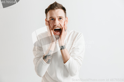 Image of The young emotional angry man screaming on garay studio background