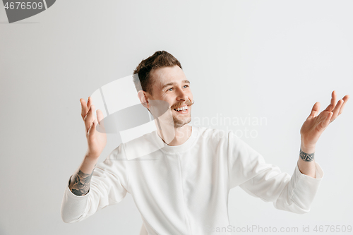 Image of The happy businessman standing and smiling against gray background.